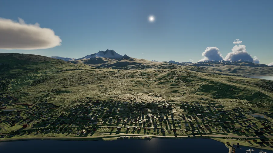 Vid utsikt fra over fjorden og dalen mot fjellene, med haugskyer og høy sol.